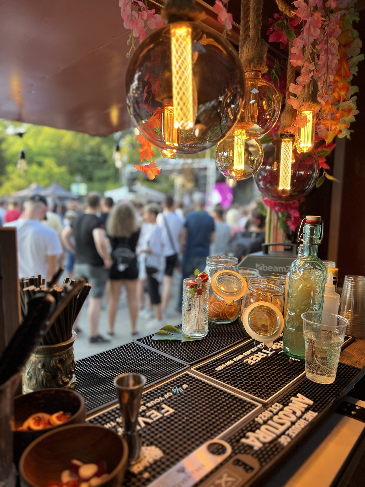 Koktélok és Edison-izzók a Tiki Foodtruck pultján, háttérben fesztiválozó tömeg
