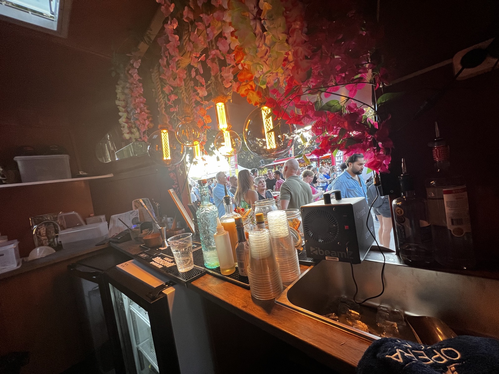 A Tiki Foodtruck bárpultja belülről, neonfénnyel és virágokkal, kint a vendégekkel